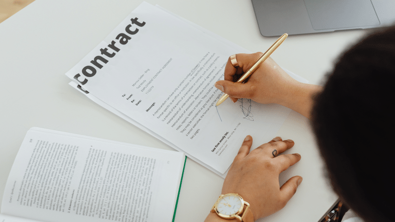 Image shows person signing an employment contract