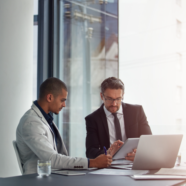Image Shows: Two people discussing something over a table with a laptop
