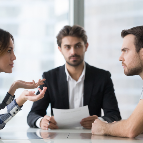 Image Shows: two people discussing a topic across the table with a moderator