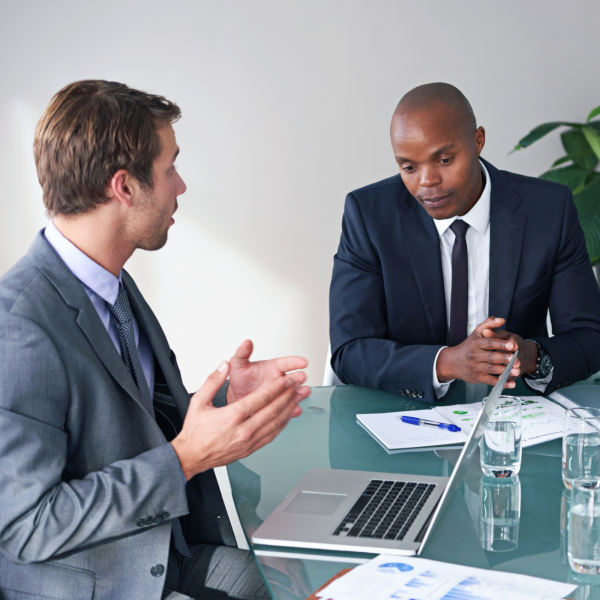 Image Shows: two people in a meeting at a desk