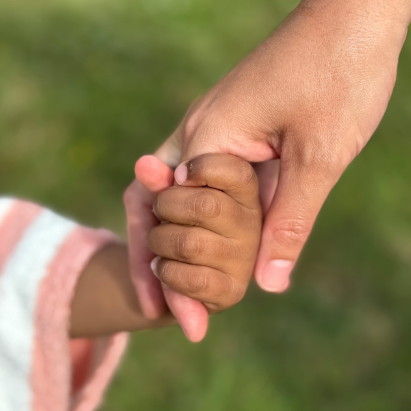 Image Shows: child holding an adults hand on grass