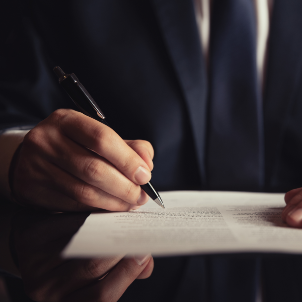 Image Shows: person signing papers close up