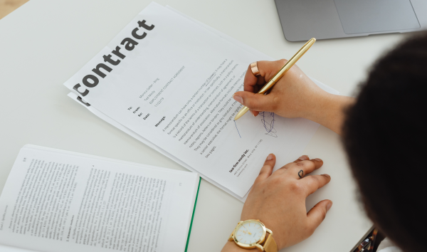 image shows person signing a contract