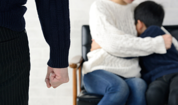 image shows man with fist and woman and child hiding