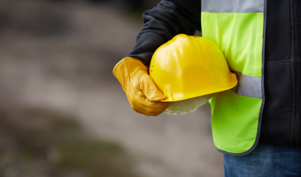 image shows construction worker hold his helmet
