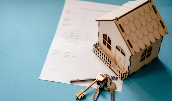 image shows little house sitting on document with keys