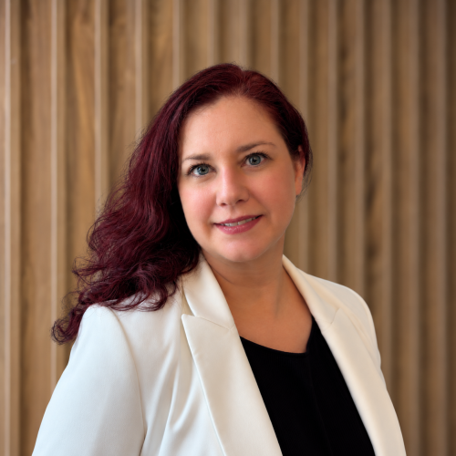Female in white jacket with black top (red hair) and a wooden background